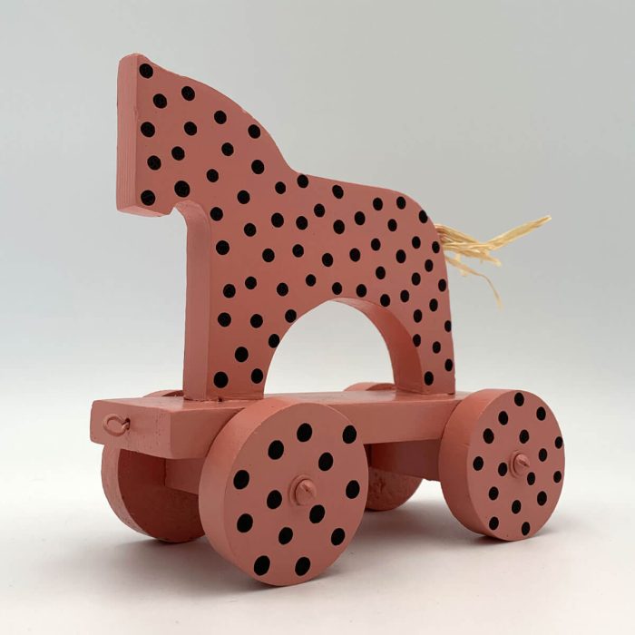 Roze houten paardje met zwarte stippen op vier wieltjes – duurzame kinderkamerdecoratie